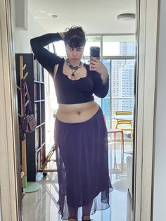 a woman taking a selfie in a mirror wearing a purple skirt and black crop top