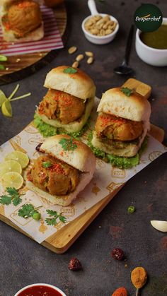 three sandwiches on a cutting board with dipping sauce