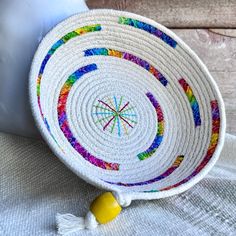 a white bowl sitting on top of a table next to a yellow ball and some tassels