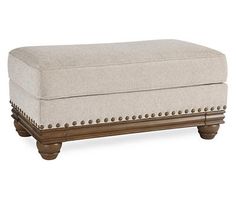 the foot stool is made from wood and has an upholstered fabric cover with studding