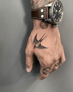 a man's hand with a tattoo on it and a watch on the wrist