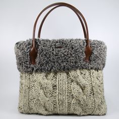 a knitted purse with leather handles on a white background