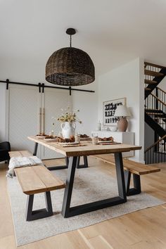 a dining table with two benches in front of it and a basket hanging from the ceiling