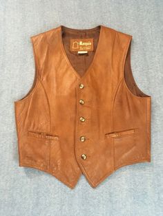 This vest by Marquis of London, is tan leather, front & back, and it is lined. It has 2 pockets and western styling. Please note measurements: chest  38" waist  36" back length from center nape  19.75" front length from shoulder to point  23.5" Western Leather Vest For Fall, Brown Sleeveless Vest For Western-themed Events, Cowboy Leather Vest, Vintage Leather Vest Outerwear, Vintage Western Leather Vest, Cowboy Jacket, Style Vest, Leather Work, Mens Clothing