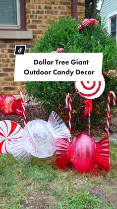 an outdoor candy decoration with red and white candies, lollipop canes, and a sign that says dollar tree giant outdoor candy decor