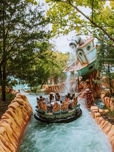 an amusement park ride with people riding in the boat and water splashing down the river