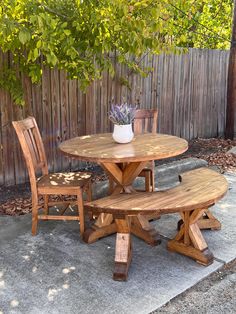 a wooden table with four chairs around it and a potted plant in the middle