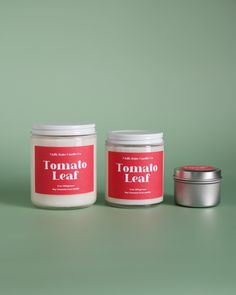 two jars of tomato leaf next to each other on a green surface with a silver tin