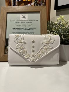 a white purse sitting on top of a table next to a framed photo and flowers