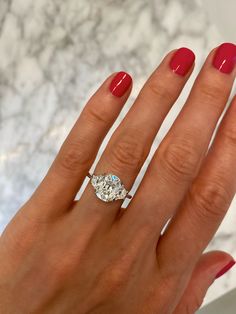 a woman's hand with a ring on it and a red manicured nail polish