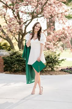 a woman in a white top and green skirt posing for the camera with her hand on her hip