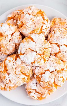 a white plate topped with powdered sugar covered pastries on top of a table