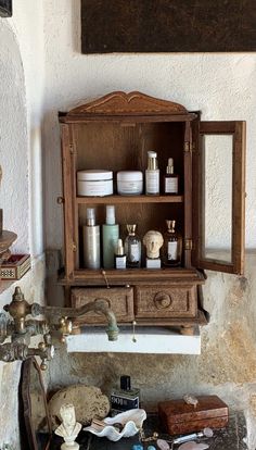 an old wooden cabinet with many bottles on the top and shelves above it, along with other antique items