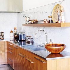 a kitchen with wooden cabinets and stainless steel counter tops, including a bowl shaped sink