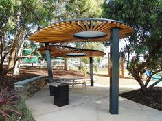 a wooden pergolated area with benches and trees