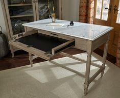 a marble top desk with drawers in a living room next to a door and window