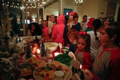 a group of children standing around a table filled with cookies and desserts on it