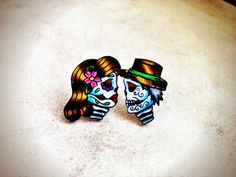 two sugar skulls wearing top hats and holding each other's heads on a table