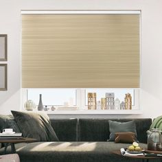 a living room with a couch, coffee table and window covered in roman blind shades