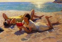 two people laying on the beach with their feet in the sand and one person holding a book