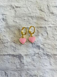 These cute and dainty gold-plated huggie earrings feature mini pink heart charms! Trendy Huggie Heart Earrings For Valentine's Day, Trendy Huggie Earrings For Valentine's Day, Pink Nickel-free Huggie Jewelry, Pink Heart Charm Huggie Jewelry, Pink Huggie Hoop Earrings Nickel Free, Pink Nickel-free Huggie Hoop Earrings, Pink Huggie Jewelry With Heart Charm, Nickel-free Pink Huggie Hoop Earrings, Pink Hypoallergenic Small Hoop Huggie Earrings