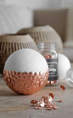 a white and gold egg sitting on top of a table next to some copper coins