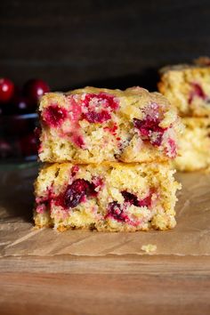 two pieces of cake sitting on top of a cutting board next to some cherries