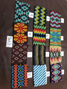 several different colored bracelets are displayed on a brown surface with price tags in front of them