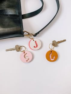 three keychains and a purse on a white surface