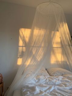 an unmade bed with white sheets and mosquito netting