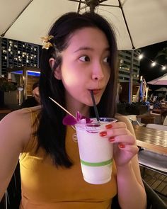 a woman drinking from a tall cup with a straw in her mouth