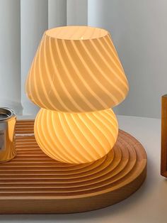 a white lamp sitting on top of a wooden table next to a canister and candle