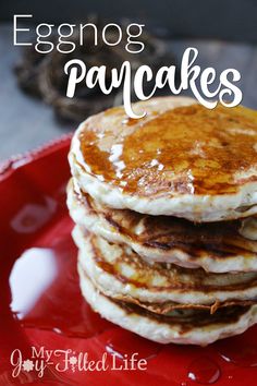 stack of eggnog pancakes on a red plate with the words eggnog pancakes