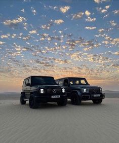 two jeeps are parked in the desert at sunset