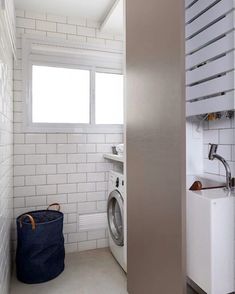 a washer sitting next to a window in a room with white tiles on the walls