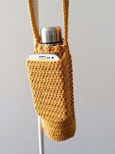 a crocheted cell phone bag hanging from a hook on a white pole in front of a wall