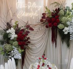 an arrangement of flowers and greenery on display at a wedding reception