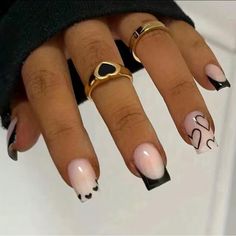 a woman's manicured nails with black and white designs on them, including two gold rings