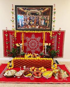 a table topped with lots of food on top of a red rug next to a painting