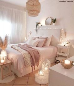 a bedroom with white walls and flooring has candles on the nightstands next to the bed