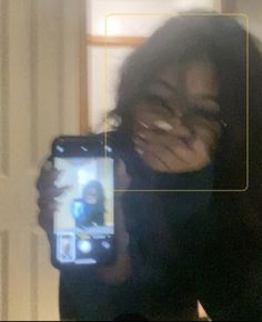 a woman taking a selfie with her cell phone in front of her face and texting on the screen