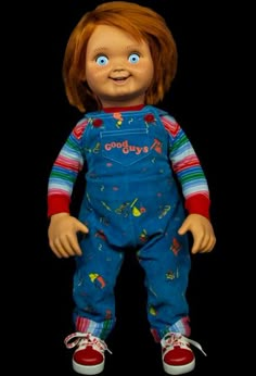 a doll with red hair and blue overalls is standing in front of a black background