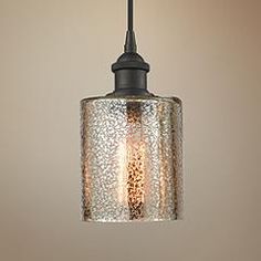 a glass light hanging from a ceiling fixture in a room with a brown wall behind it