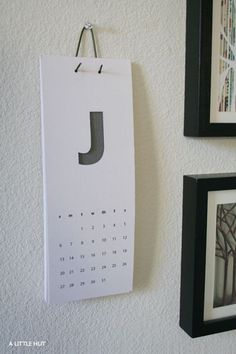 a calendar hangs on the wall next to two framed pictures