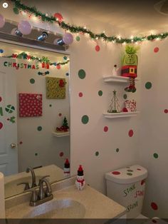 a bathroom decorated for christmas with lights and decorations on the wall, toilet and sink