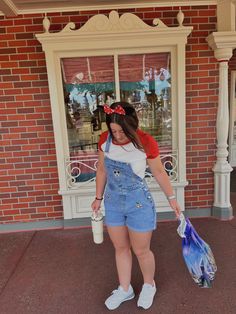 a woman in overalls holding a blue bag