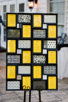 a black and yellow wedding seating chart on a stand with scissors in front of it