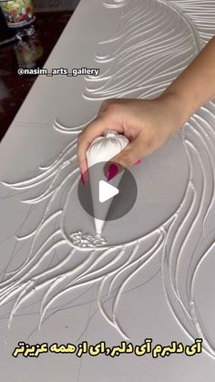 a person is using a brush to paint the design on a piece of white paper