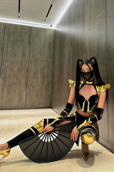 a woman dressed in black and gold sitting on the floor with her legs spread out