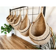 several baskets hanging on a wall near a potted plant